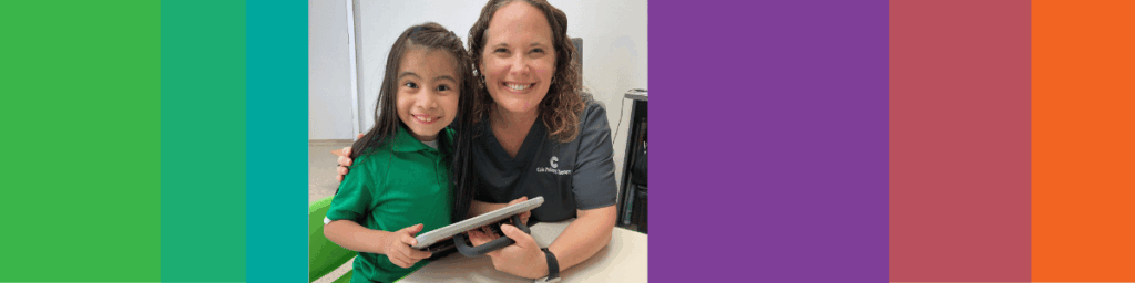 speech therapists smiles with patient while holding an aac device
